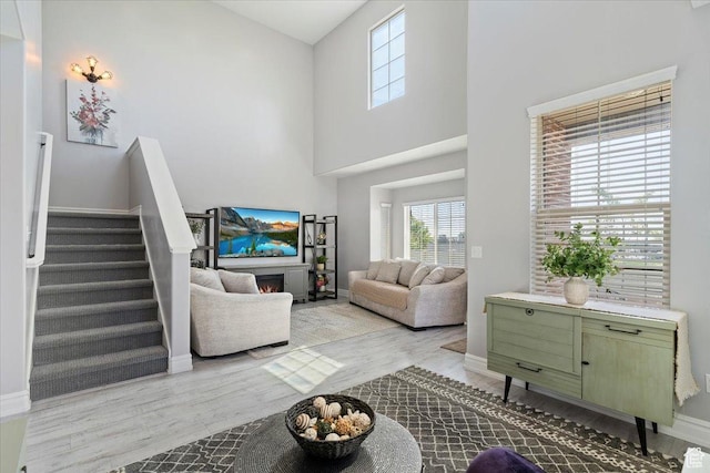 160 S 2875 W, West Point, UT 84015 - living area with wood finished floors, a high ceiling, baseboards, stairs, and a warm lit fireplace