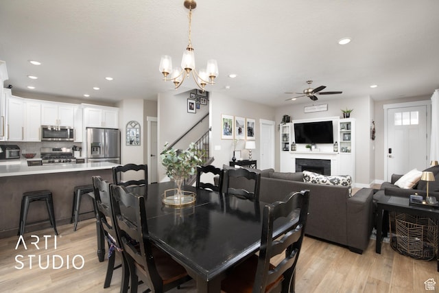 3516 N Willy Way, Eagle Mountain, UT 84005 - dining room featuring light wood-type flooring, a ceiling fan, recessed lighting, a chandelier, and a fireplace