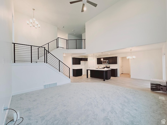 13494 S Dawes Ln W Unit 1703, Riverton, UT 84096 - unfurnished living room featuring a chandelier, high vaulted ceiling, light colored carpet, a ceiling fan, and stairs