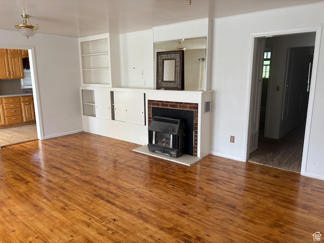 622 S Main St, Gunnison, UT 84634 - unfurnished living room featuring a wood stove, light wood-type flooring, baseboards, and built in shelves