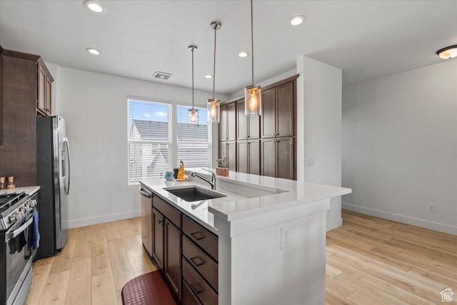 10849 S Lake Run Rd Unit 187, South Jordan, UT 84009 - kitchen with stainless steel appliances, a sink, a center island with sink, light wood-style floors, and baseboards