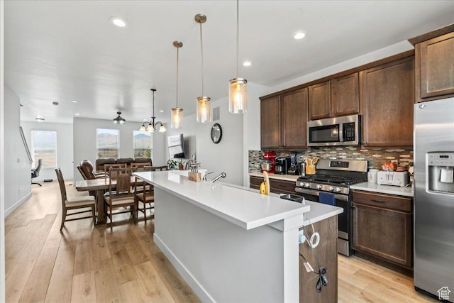 10849 S Lake Run Rd Unit 187, South Jordan, UT 84009 - kitchen with stainless steel appliances, an island with sink, light countertops, tasteful backsplash, and dark brown cabinetry