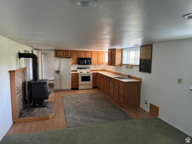 67 S 200 E, Pleasant Grove, UT 84062 - kitchen featuring white appliances, light countertops, brown cabinetry, a sink, and a wood stove