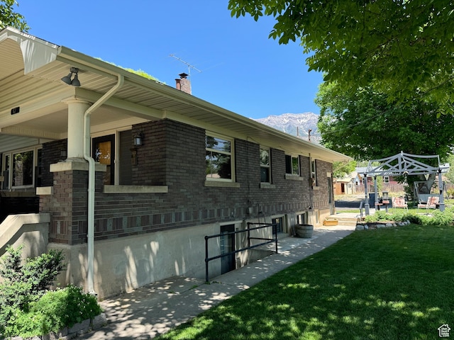 67 S 200 E, Pleasant Grove, UT 84062 - view of home's exterior with a chimney, a lawn, brick siding, and a mountain view