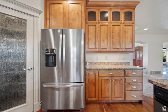 503 W 650 S, Orem, UT 84058 - kitchen featuring stainless steel fridge, arched walkways, brown cabinets, glass insert cabinets, and light stone counters