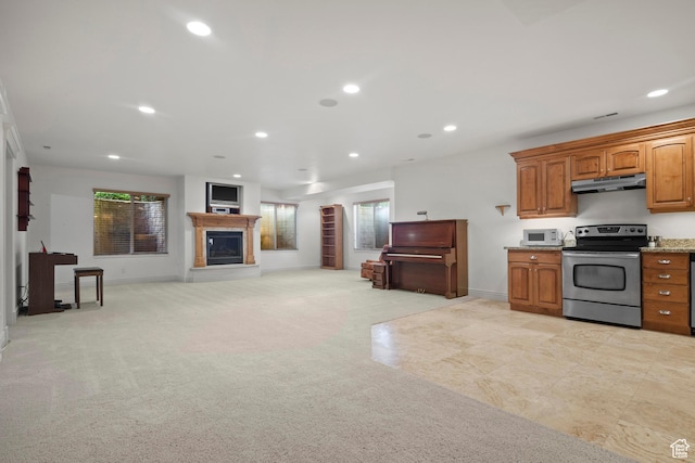 503 W 650 S, Orem, UT 84058 - kitchen featuring stainless steel electric stove, white microwave, under cabinet range hood, a glass covered fireplace, and brown cabinetry
