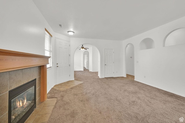 282 Caleb Dr, North Salt Lake, UT 84054 - unfurnished living room with arched walkways, a fireplace, light carpet, a ceiling fan, and baseboards