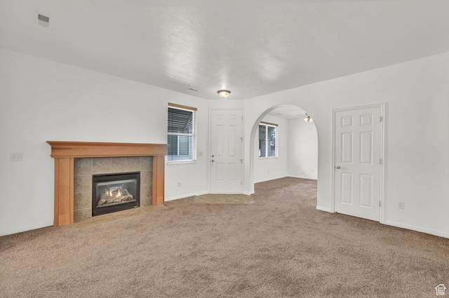 282 Caleb Dr, North Salt Lake, UT 84054 - unfurnished living room featuring carpet, a tiled fireplace, arched walkways, and baseboards
