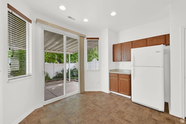 282 Caleb Dr, North Salt Lake, UT 84054 - kitchen with freestanding refrigerator, healthy amount of natural light, baseboards, brown cabinets, and recessed lighting