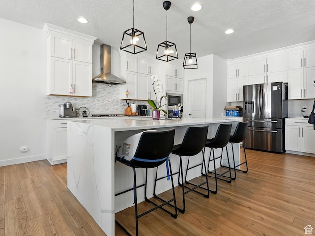 3287 S Boots Way, Syracuse, UT 84075 - kitchen featuring wall chimney exhaust hood, stainless steel fridge with ice dispenser, backsplash, light countertops, and an island with sink
