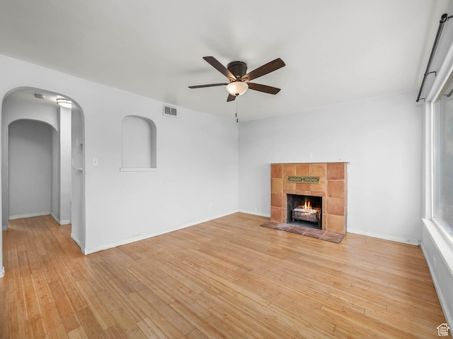 990 W 300 N, Provo, UT 84601 - unfurnished living room with a ceiling fan, light wood-style flooring, a tile fireplace, arched walkways, and baseboards