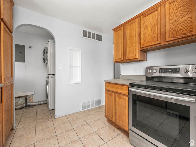 990 W 300 N, Provo, UT 84601 - kitchen featuring stainless steel range with electric cooktop, stacked washing machine and dryer, electric panel, arched walkways, and brown cabinetry