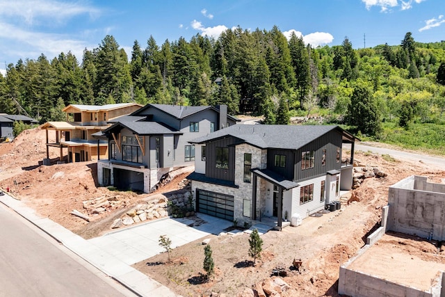 4107 W Crest Ct, Park City, UT 84098 - view of front facade with concrete driveway, board and batten siding, an attached garage, stone siding, and a forest view