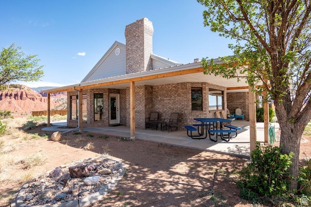 397 N Wendy Dr, Torrey, UT 84775 - rear view of property featuring brick siding, a patio, and a chimney