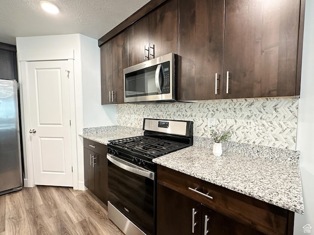290 E 1825 N Unit 58, North Ogden, UT 84414 - kitchen featuring appliances with stainless steel finishes, dark brown cabinetry, light wood-type flooring, backsplash, and a textured ceiling