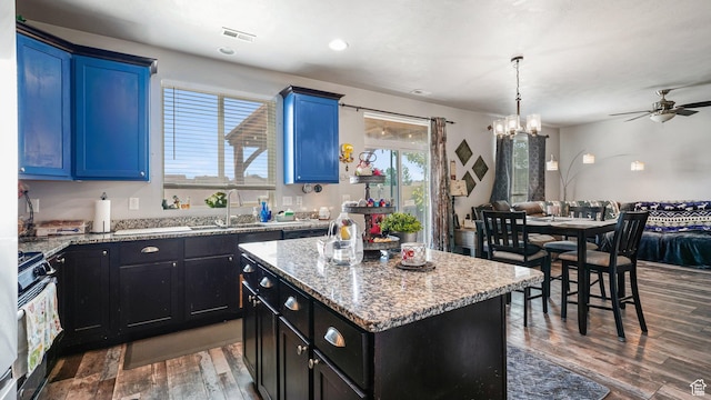 1002 W Stonehaven Dr Unit 108, North Salt Lake, UT 84054 - kitchen with wood finished floors, a ceiling fan, a sink, gas stove, and a center island