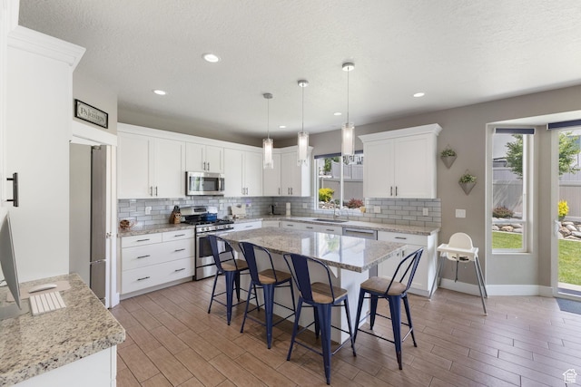 776 W Horizon Dr, Lehi, UT 84043 - kitchen with appliances with stainless steel finishes, decorative backsplash, a kitchen bar, light wood finished floors, and recessed lighting