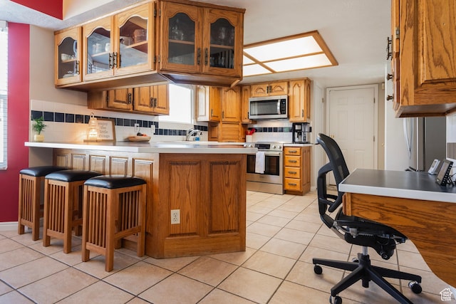 9039 S 1660 E, Sandy, UT 84093 - kitchen with stainless steel appliances, a peninsula, light tile patterned floors, glass insert cabinets, and brown cabinets