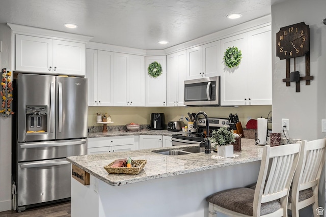 177 E 610 S, Santaquin, UT 84655 - kitchen featuring appliances with stainless steel finishes, a peninsula, white cabinetry, dark wood-type flooring, and light stone countertops