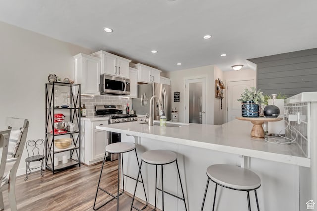 14496 S Edgemere Dr W, Herriman, UT 84096 - kitchen featuring stainless steel appliances, a sink, a breakfast bar area, backsplash, and white cabinetry