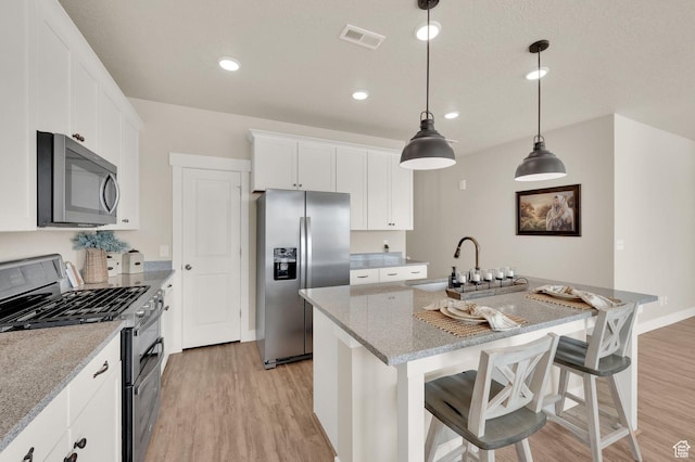 3154 S Edgewater Ln W, Syracuse, UT 84075 - kitchen with stainless steel appliances, light wood-style floors, a sink, a kitchen island with sink, and white cabinetry