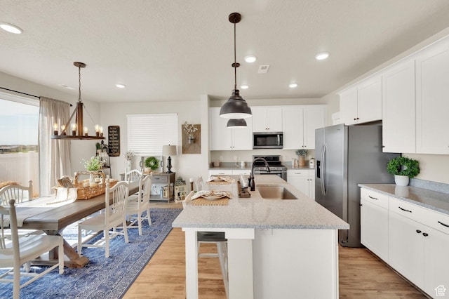 3154 S Edgewater Ln W, Syracuse, UT 84075 - kitchen featuring stainless steel appliances, a sink, light wood-style flooring, a center island with sink, and recessed lighting