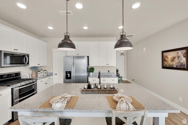 3154 S Edgewater Ln W, Syracuse, UT 84075 - kitchen with appliances with stainless steel finishes, a kitchen island, white cabinetry, a kitchen breakfast bar, and recessed lighting