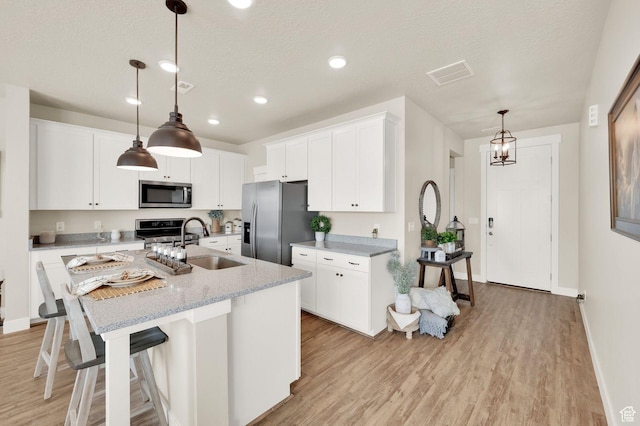 3154 S Edgewater Ln W, Syracuse, UT 84075 - kitchen with appliances with stainless steel finishes, a sink, light wood finished floors, white cabinetry, and recessed lighting