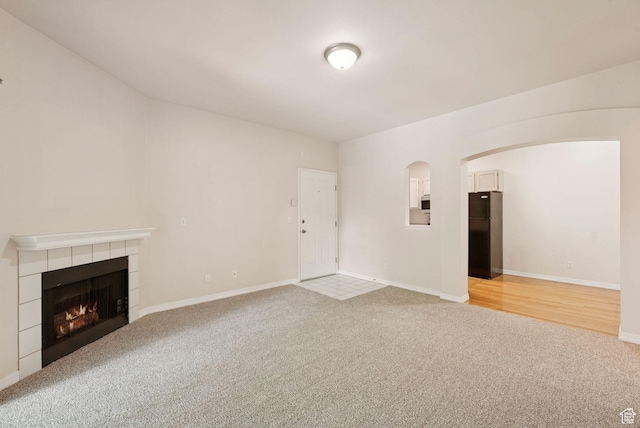 150 S 800 E Unit A9, Salt Lake City, UT 84102 - unfurnished living room with light colored carpet, a tiled fireplace, baseboards, and arched walkways