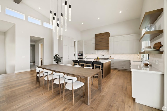 7175 Lupine Dr, Park City, UT 84098 - kitchen featuring open shelves, a towering ceiling, a kitchen island, light wood-type flooring, and light countertops