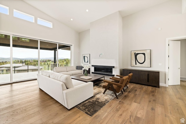 7175 Lupine Dr, Park City, UT 84098 - living area featuring high vaulted ceiling, healthy amount of natural light, a glass covered fireplace, hardwood / wood-style floors, and baseboards