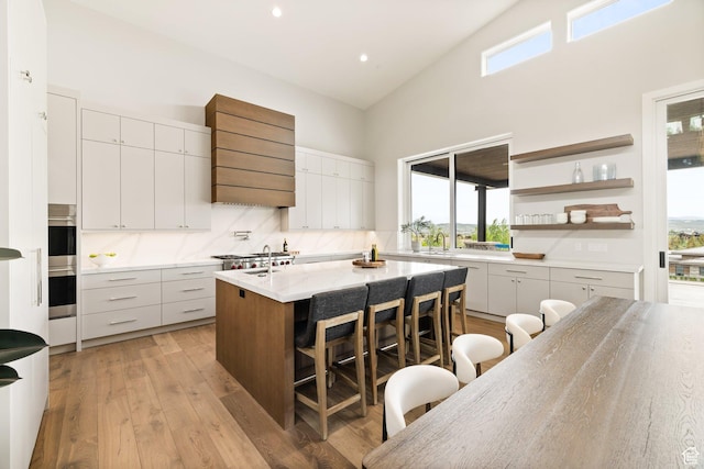 7175 Lupine Dr, Park City, UT 84098 - kitchen with a breakfast bar, high vaulted ceiling, a center island with sink, healthy amount of natural light, and wall chimney range hood