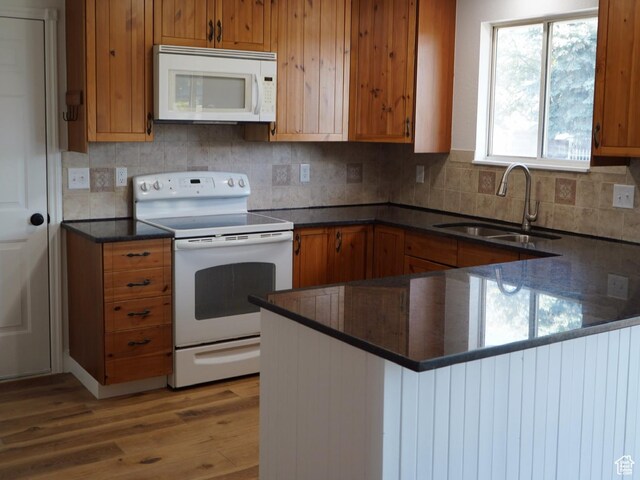 1102 E 120 S, Spanish Fork, UT 84660 - kitchen featuring white appliances, brown cabinetry, light wood-type flooring, a sink, and a peninsula