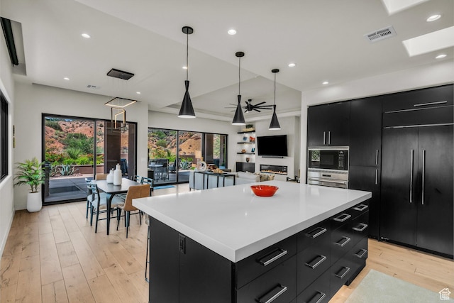 2304 N Cohonina Trl, St George, UT 84770 - kitchen with dark cabinets, built in appliances, a center island, light countertops, and light wood-style flooring
