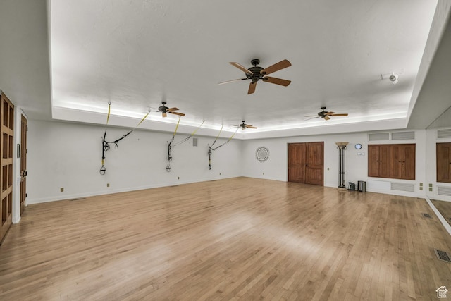2304 N Cohonina Trl, St George, UT 84770 - unfurnished living room with a tray ceiling, light wood-style floors, baseboards, and ceiling fan