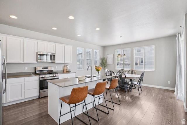 1123 W Osprey Dr, Stansbury Park, UT 84074 - kitchen featuring appliances with stainless steel finishes, a breakfast bar area, dark wood-style floors, baseboards, and white cabinetry