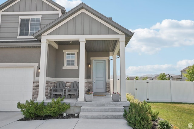 1123 W Osprey Dr, Stansbury Park, UT 84074 - view of front of house featuring a porch, board and batten siding, stone siding, and a gate