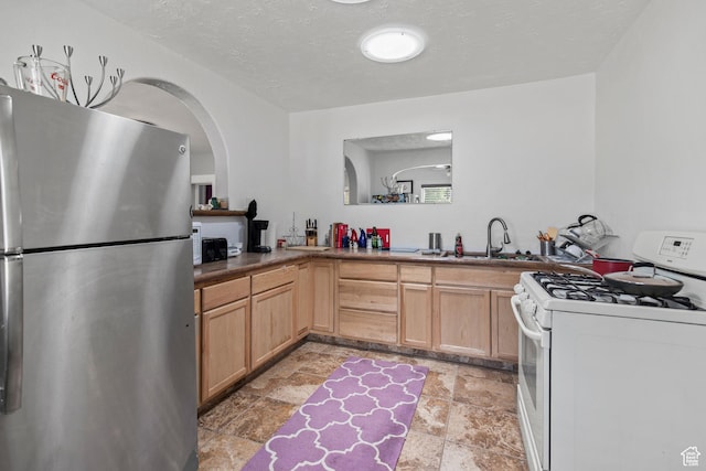 195 S 200 E, Monroe, UT 84754 - kitchen featuring freestanding refrigerator, white range with gas stovetop, light stone finish floors, a sink, and light brown cabinets