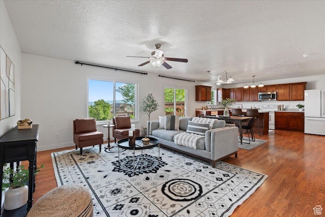 6286 W Anders Ridge Way S, West Valley City, UT 84128 - living area featuring wood finished floors, ceiling fan, a textured ceiling, a chandelier, and baseboards