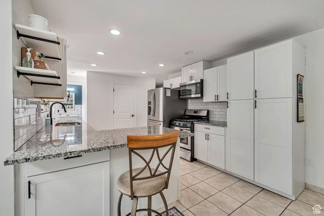 10453 S 2775th St W, South Jordan, UT 84095 - kitchen with stainless steel appliances, a sink, decorative backsplash, a peninsula, and white cabinetry