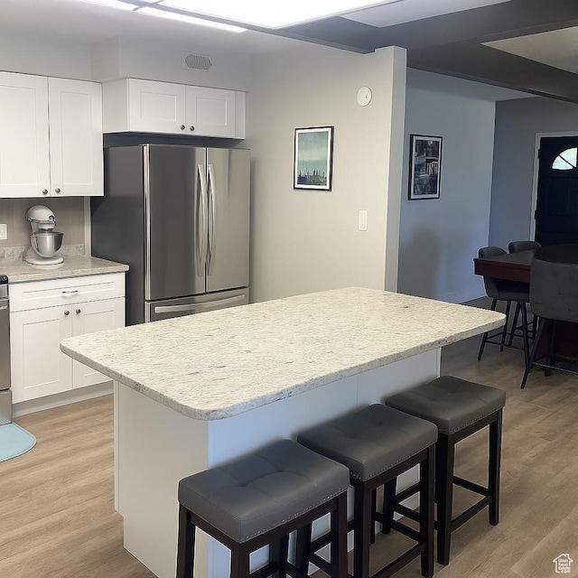 3480 S 4000th Rd W, Delta, UT 84624 - kitchen with freestanding refrigerator, a kitchen bar, light wood-style flooring, and white cabinetry