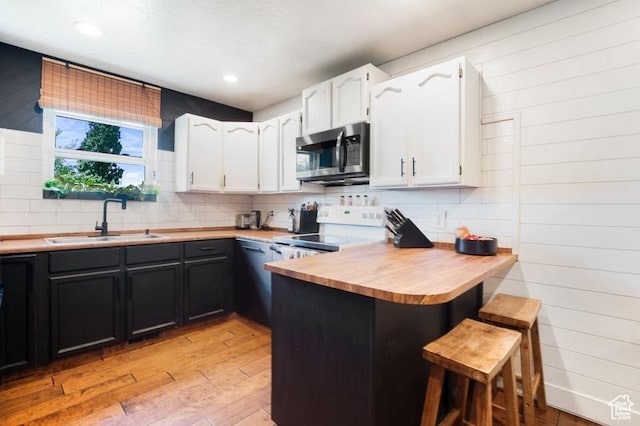 3186 W 5925 S, Roy, UT 84067 - kitchen featuring stainless steel microwave, electric range oven, a sink, light wood-style flooring, and a breakfast bar area