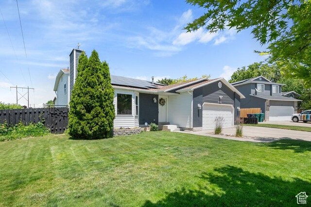3186 W 5925 S, Roy, UT 84067 - view of front facade featuring a garage, solar panels, concrete driveway, and a chimney