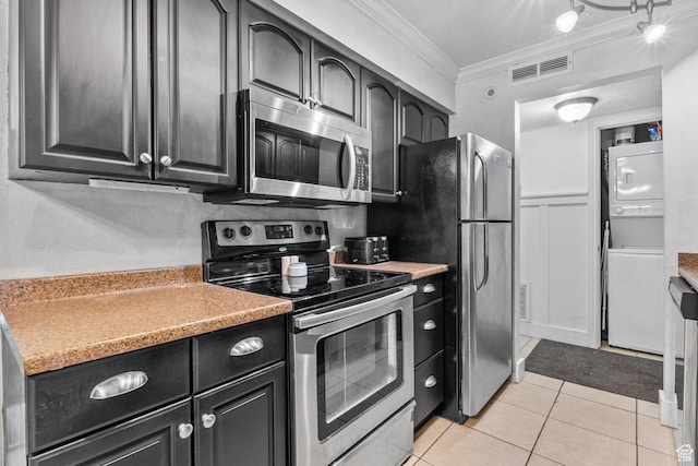 66 W Lester Ave Unit K27, Murray, UT 84107 - kitchen with stacked washing machine and dryer, stainless steel appliances, ornamental molding, light tile patterned floors, and dark cabinets