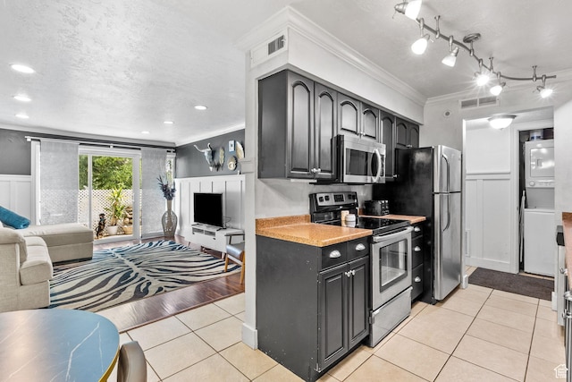 66 W Lester Ave Unit K27, Murray, UT 84107 - kitchen with estacked washer and dryer, stainless steel appliances, crown molding, open floor plan, and light countertops