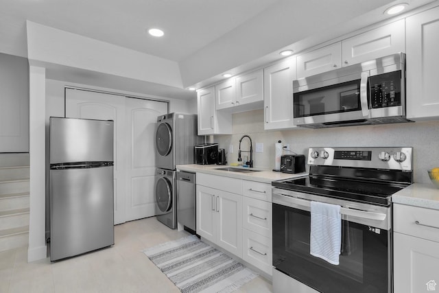 1677 N 2640 W, Lehi, UT 84043 - kitchen with stainless steel appliances, stacked washer / drying machine, a sink, light countertops, and white cabinetry