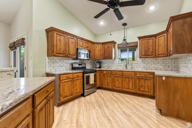 114 E Canterwood Dr, Washington, UT 84780 - kitchen featuring appliances with stainless steel finishes, a sink, brown cabinets, light wood-style flooring, and lofted ceiling