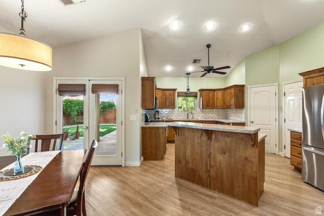 114 E Canterwood Dr, Washington, UT 84780 - kitchen with freestanding refrigerator, lofted ceiling, brown cabinets, tasteful backsplash, and a ceiling fan