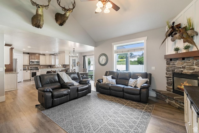 580 N Cherry Ridge Ln, Richmond, UT 84333 - living area with a ceiling fan, light wood-type flooring, lofted ceiling, a stone fireplace, and a chandelier