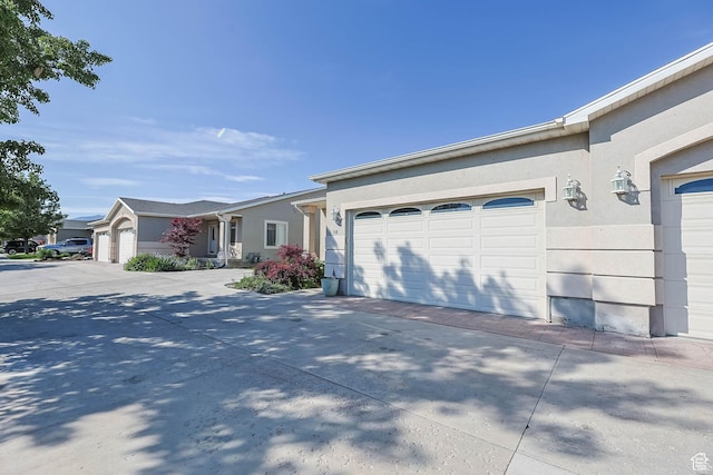 18 Clubhouse Dr, Stansbury Park, UT 84074 - view of front of home featuring an attached garage, concrete driveway, and stucco siding